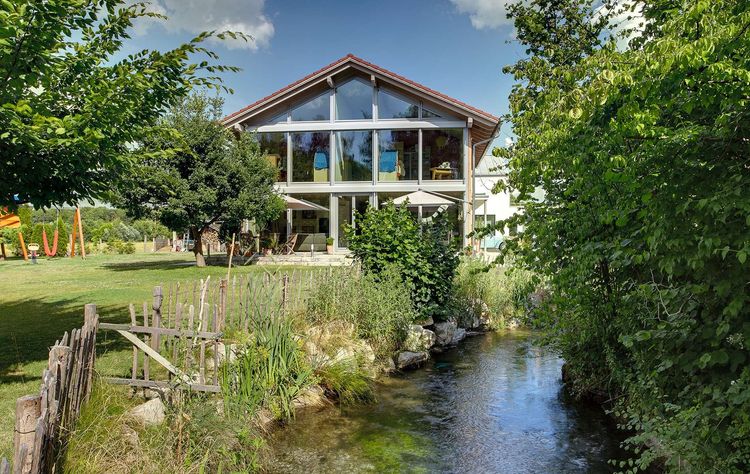 Die Glasfront des Holzhauses im Landhausstil mit durchgängiger Holzfassade