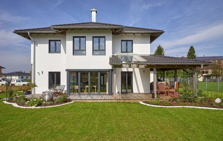 Modernes Holzhaus im Stadtvilla-Stil mit mineralischem Außenputz und teilweise überdachter Terrasse