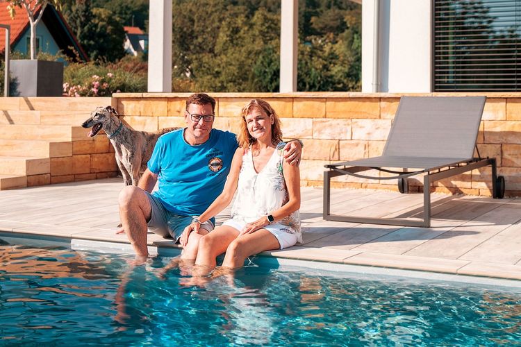 Baufamilie am Pool ihres Fertighauses