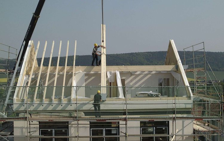 Dachbalken werden beim Rohbau platziert