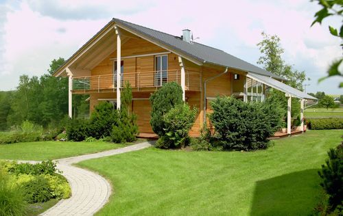 Holzhaus im Landhausstil, geschickt eingesetzte Mischfassade aus mineralischem Außenputz und Lärchenholz, Schiebläden elektrisch verstellbar