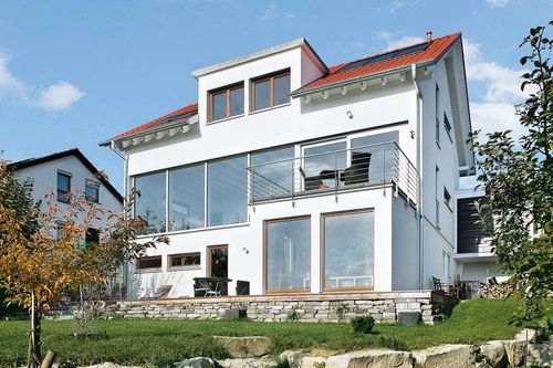 Ein modernes Haus mit Terrasse im Obergeschoss.