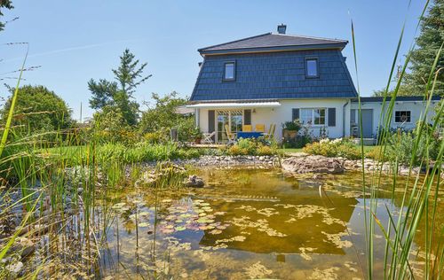 Modernes Holzhaus in barockem Stil mit Masard-Walmdach und mineralischem Außenputz