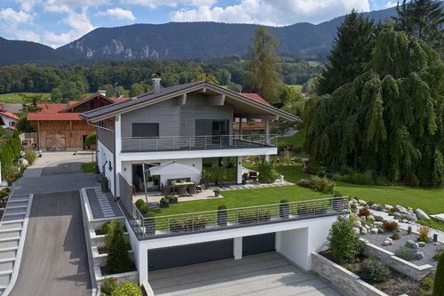 Traditionelles Holzhaus mit Mischfassade aus Lärchenholz und Putz, mit flachem Satteldach und hohem Kniestock