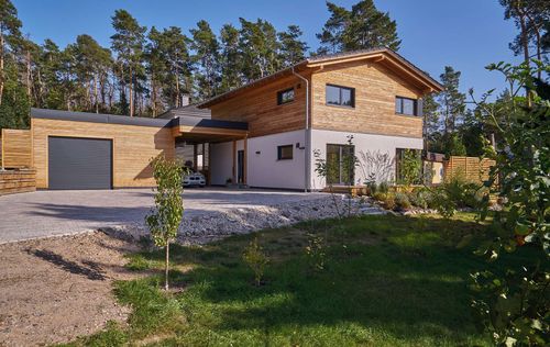 Modernes Holzhaus im voralpenstil mit Mischfassade aus Lärchenholz und mineralischem Putz, Anbau mit Flachdach