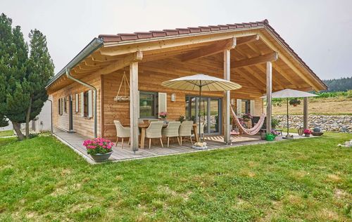 Bungalow aus Holz mit umlaufender, teilweise überdachter Terrasse