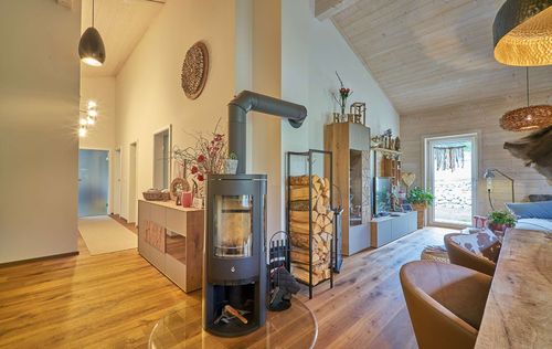 Der Kachelofen des Bungalows aus Holz mit umlaufender, teilweise überdachter Terrasse