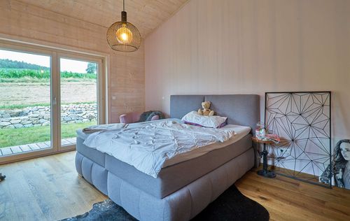 Das Schlafzimmer des Bungalows aus Holz mit umlaufender, teilweise überdachter Terrasse