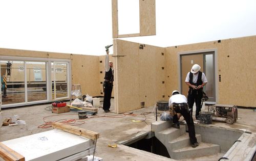 Bauarbeiter beim Aufbau eines Fertighauses auf der Baustelle