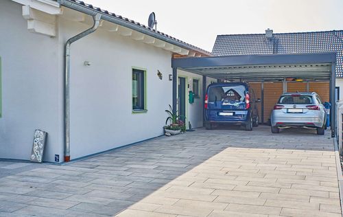 Die Einfahrt des Bungalows aus Holz mit Putzfassade