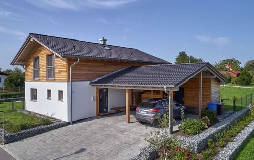 Traditionelles Holzhaus mit Mischfassade aus Lärchenholz und Putz, mit flachem Satteldach und hohem Kniestock