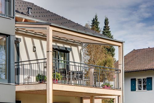 Der Balkon des modernen Zweifamilienhauses aus Holz mit Wintergarten