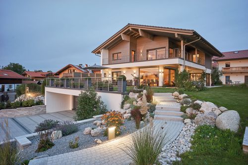 Modernes Holzhaus mit Mischfassade aus Holz und Putz mit vielen Glaselementen und barrierefreiem Zugang 