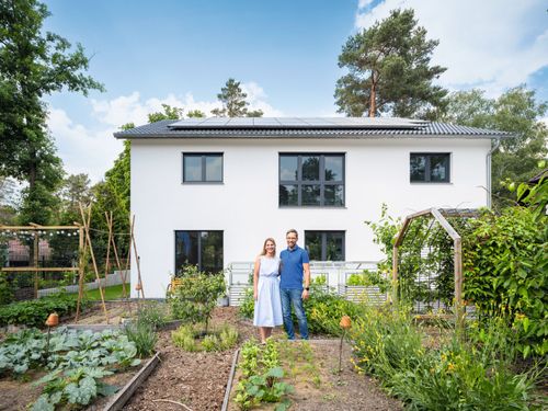 Baufamilie im Garten vor ihrem Fertighaus