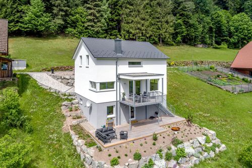 Außenansicht des Beilharz Modulhauses Pure 772 in Hanglage mit Satteldach, Garten und Terrasse