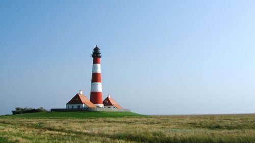 Nordischer Leuchtturm mit grüner Wiese im Vordergrund