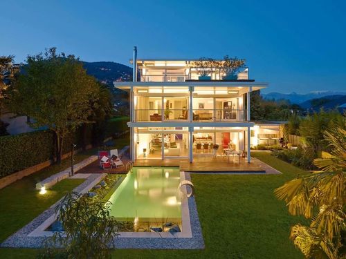 Moderner Holz-Skelettbau mit Dachterrasse, Pool im Garten und Abendbeleuchtung